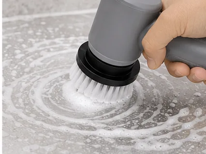A hand using the Detail scrubber to work soap suds across a wet stone surface